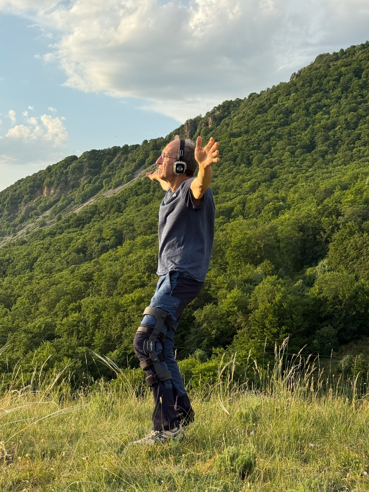 Homme bras levés face à la montagne verdoyante